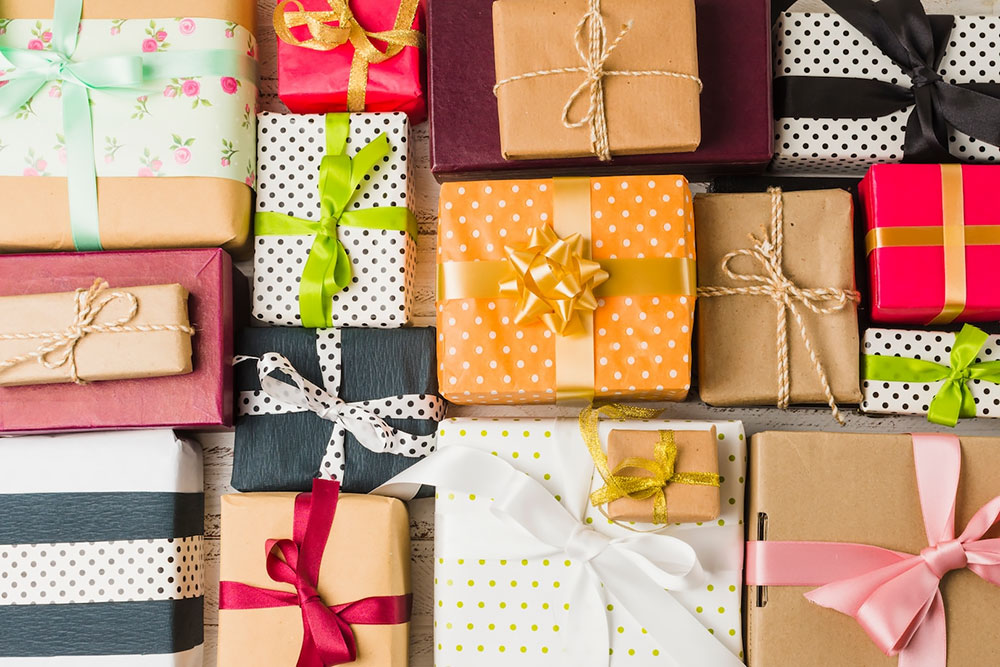 A variety of colorful wrapped gift boxes with different ribbons and bows are arranged together, reminiscent of a delightful reward from a loyalty program.